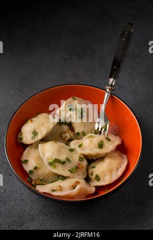 Kartoffelknödel mit gebratenem Speck und grünen Zwiebeln Stockfoto