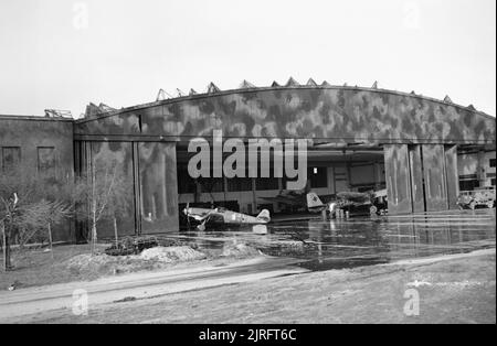 Eine verlassene Messerschmitt Bf 109 G und ein paar Ju 88 G Nacht-Kämpfer in einem Hangar in Wunstorf Flugplatz in Deutschland, durch 6 Airborne Division gefangen, 8. April 1945. Me 109 und Ju 88 G von Luftfahrzeugen, die in einem Hangar am Wunstorf Flugplatz, von der 5. Parachute Brigade, 6 Airborne Division, 8. April 1945 festgehalten. Stockfoto