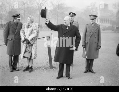 Winston Churchill wirft seinen Hut in der Salute, die während einer Inspektion der 1. Amerikanischen Geschwaders der Home Guard auf Horse Guards Parade in London, den 9. Januar 1941. Winston Churchill wirft seinen Hut in der Salute, die während einer Inspektion der 1. Amerikanischen Geschwaders der Home Guard auf Horse Guards Parade in London, den 9. Januar 1941. Hinter, Frau Churchill Chats zu einem Wachen Officer. Generalleutnant Sir Bertram N Sergison-Brooke (GOC London Area) steht auf der rechten Seite. Stockfoto