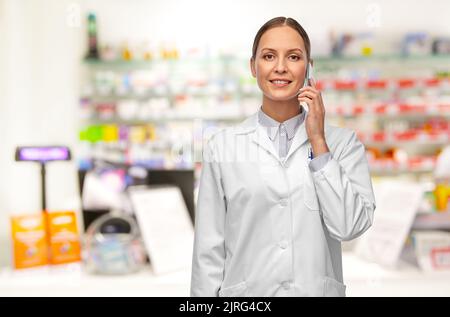 Weibliche Doktorin, die in der Apotheke auf dem Smartphone anruft Stockfoto