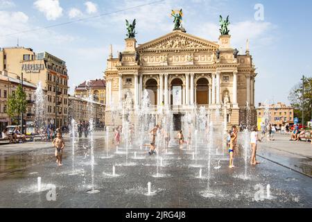 Lviv, Ukraine - 24. August 2022: Kinder spielen im Brunnen in der Nähe der Nationaloper von Lviv Stockfoto