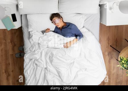 Junge Frau in Maske schlafen im Bett zu Hause Stockfoto