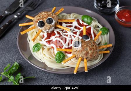 Koteletts sehen aus wie Spinnen mit Oliven und Trinkhalmen, serviert mit Spaghetti-Nudeln und Tomatensauce. Halloween Frühstück oder Mittagessen Idee für Kinder Stockfoto