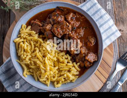 Ungarischer Gulasch mit Spätzle-Nudeln auf einem Teller Stockfoto
