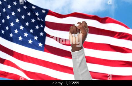 die Hand einer afrikanischen Frau zeigt die Faust auf dem amerikanischen Glag Stockfoto