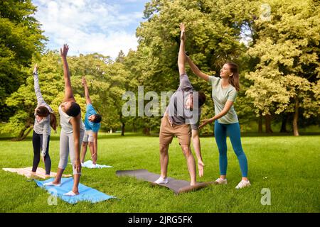 Gruppe von Menschen, die Yoga mit einem Lehrer im Park machen Stockfoto