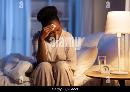 Gestresste afrikanische Frau, die nachts im Bett liegt Stockfoto
