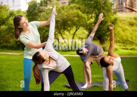 Gruppe von Menschen, die Yoga mit einem Lehrer im Park machen Stockfoto