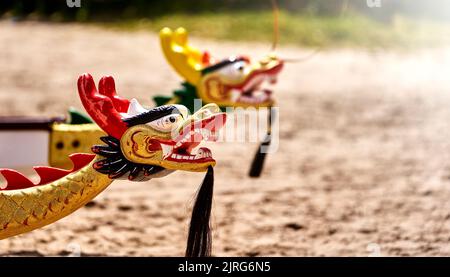 Schwarz, rot und Gold lackierter Drachenkopf aus Holz mit Kinnbart am Bug eines Drachenbootes, selektiver Fokus Stockfoto