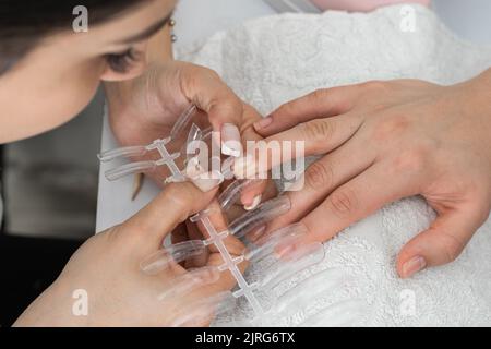 latina Manikurist Herstellung eines Polygel Nägel. Nehmen Sie das Maß in den falschen Nägel, die verschiedene Formen und Größen haben, um die zu wählen, die am besten passt y Stockfoto