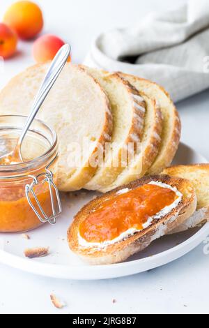 Geröstete Brotscheiben mit Frischkäse und Aprikosenaufstrich, fertig zum Essen. Stockfoto