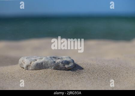 Steine auf einem weißen Sandstrand Hintergrund. Minimaler kreativer Kompositionshintergrund für Kosmetik oder Produktpräsentation. Vorderansicht Stockfoto