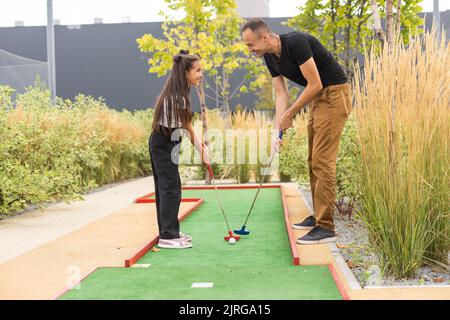 Vater und Tochter spielen gemeinsam im Park Minigolf Stockfoto