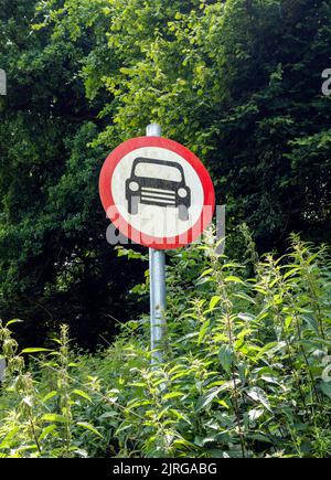 Keine Kraftfahrzeuge Zeichen zwischen Flora in überwuchert Landstraße Stockfoto