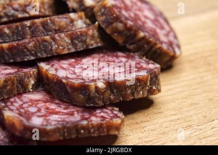 Nahaufnahme einer in Scheiben geschnittenen Salami auf dem Tisch. Stücke von köstlicher Räucherwurst auf einem Schneidebrett. Stockfoto