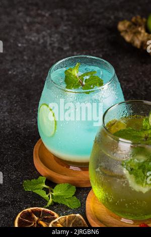 Mehrere Cocktails im Glas mit Eiswürfel, Erdbeere, Limette, Ingwer und Minzblatt auf dem Texturtisch Stockfoto