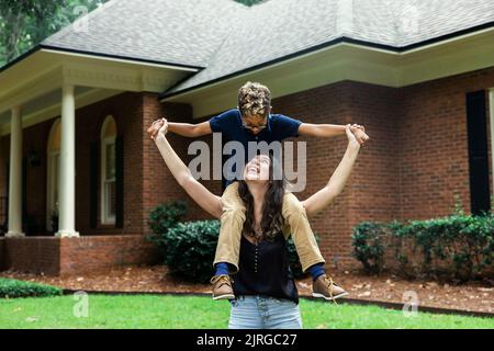 Eine große Schwester hält ihren kleinen Bruder auf den Schultern für ein lustiges Porträt Stockfoto