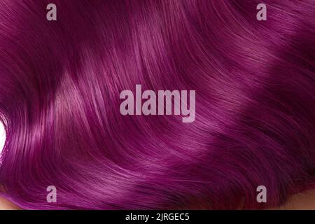 Eine Nahaufnahme von einem Haufen glänzendem, glattem, violettem Haar in einem gewellten, geschwungenen Stil Stockfoto