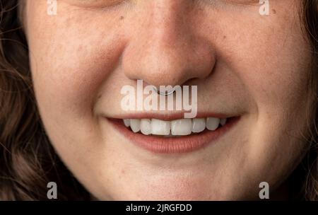 Nahaufnahme einer jungen Frau mit durchbohrter Nase und lächelnd. Stockfoto