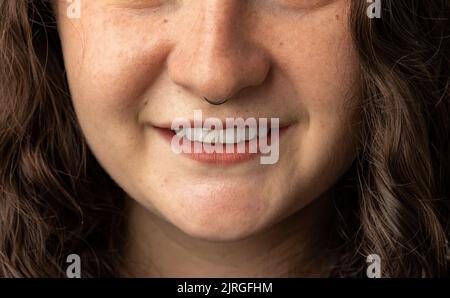 Nahaufnahme einer jungen Frau mit durchbohrter Nase und lächelnd. Stockfoto