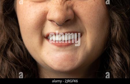 Nahaufnahme einer schönen jungen Frau, die ihre Nase hochdreht, mit Nasenring Stockfoto