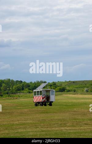 Ein Beobachtungsstand, der mit Sonnenkollektoren in einem grünen Feld unter bewölktem Himmel arbeitet Stockfoto