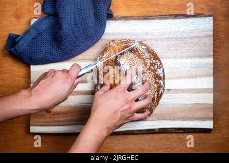 Sauerteigbrot auf einem Holzbrett schneiden Stockfoto