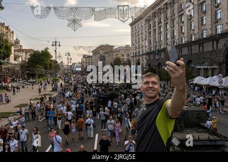 Kiew, Oblast Kiew, Ukraine. 21. August 2022. Ein Mann macht ein Selfie mit dem Hintergrund einer Menge, die gekommen ist, um die zerstörte russische Militärausrüstung in der Ausstellung auf den Straßen von Kiew zu sehen. Zum bevorstehenden Unabhängigkeitstag der Ukraine und fast 6 Monate nach der umfassenden Invasion der Ukraine am 24. Februar veranstaltet die Hauptstadt Kiew in der Hauptstraße der Chreschajtk-Straße eine Ausstellung mit mehreren zerstörten Militärgeräten, Panzer und Waffen der Streitkräfte der Russischen Föderation (AFRF).als die russische vollständige Invasion der Ukraine am Februar begann Stockfoto