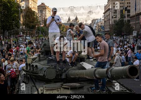 Kiew, Oblast Kiew, Ukraine. 21. August 2022. Jugendliche und Kinder klettern auf die Spitze eines Wracks eines russischen Panzers, als Menschen strömten, um die Ausstellung zerstörter russischer Panzer auf den Straßen von Kiew zu sehen. Zum bevorstehenden Unabhängigkeitstag der Ukraine und fast 6 Monate nach der umfassenden Invasion der Ukraine am 24. Februar veranstaltet die Hauptstadt Kiew in der Hauptstraße der Chreschajtk-Straße eine Ausstellung mit mehreren zerstörten Militärgeräten, Panzer und Waffen der Streitkräfte der Russischen Föderation (AFRF).als die russische vollständige Invasion der Ukraine begann Stockfoto