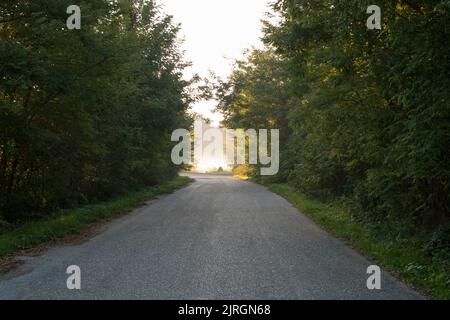 Die Straße, die an der Biegung durch Sonnenlicht beleuchtet wird. Sie vertreten die Inspiration, Gottes Erscheinungen, Aufklärung Stockfoto