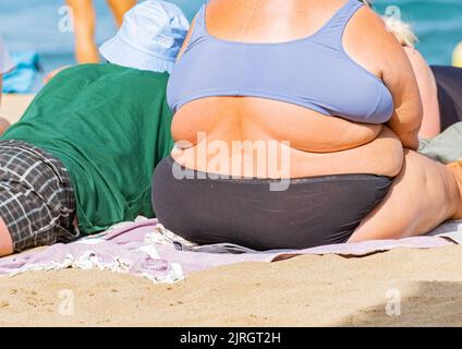 Übergewichtige Frau beim Sonnenbaden am Strand in Spanien Stockfoto