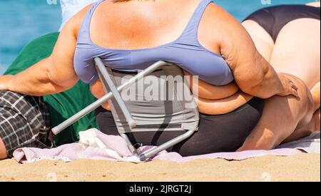 Übergewichtige Frau beim Sonnenbaden am Strand in Spanien Stockfoto