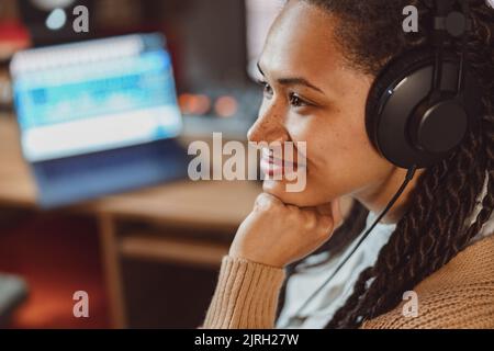Nahaufnahme charmante afrikanische Frau, Songwriterin, Toningenieurin, Sängerin mit Kopfhörern, die an einem Musikstudio arbeitet Stockfoto