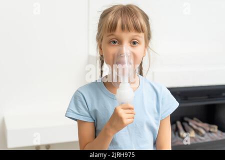 Kid girl macht Inhalation mit einem Vernebler. Krankes Kind hält Inhalator in der Hand und atmet durch einen Inhalator zu Hause Stockfoto