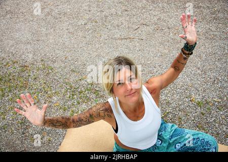 Junge europäische Dame mit ausgestreckten Armen, mit Tattoos und Piercings Stockfoto