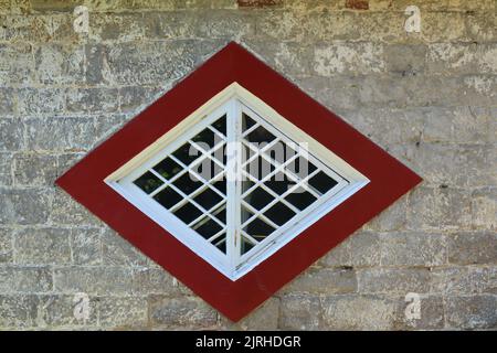 Ein ungewöhnliches diamantförmiges Fenster auf einem historischen Haus in Devon, England Stockfoto