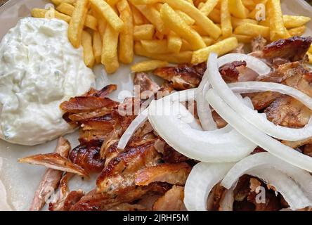 Nahaufnahme von isolierten bereit, griechische Schweinefleisch Gyros Platte mit Zwiebeln, pommes frites und tzatziki Dip zu essen Stockfoto