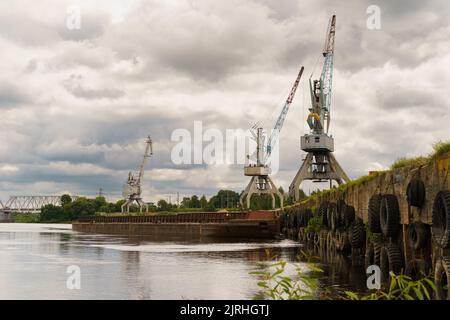 Transport- und Frachtkonzept. Krane im Hafen bei der Verladung des Wassertransports. Stockfoto