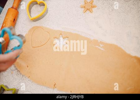 Frau Hände Formen Formen Kutter Ingwerteig und macht leckere weihnachten Ingwerkekse. Kochen und Dekorieren weihnachtsdessert. Stockfoto