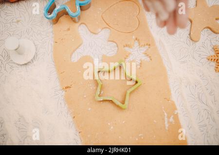 Frau Hände Formen Formen Kutter Ingwerteig und macht leckere weihnachten Ingwerkekse. Kochen und Dekorieren weihnachtsdessert. Stockfoto