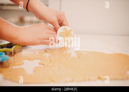 Frau Hände Formen Formen Kutter Ingwerteig und macht leckere weihnachten Ingwerkekse. Kochen und Dekorieren weihnachtsdessert. Stockfoto