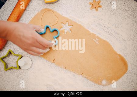 Frau Hände Formen Formen Kutter Ingwerteig und macht leckere weihnachten Ingwerkekse. Kochen und Dekorieren weihnachtsdessert. Stockfoto