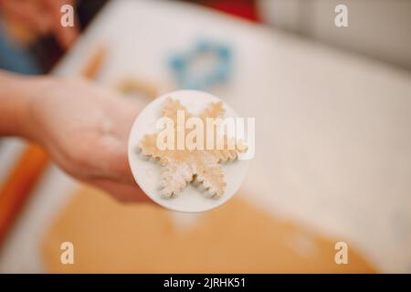 Frau Hände Formen Formen Kutter Ingwerteig und macht leckere weihnachten Ingwerkekse. Kochen und Dekorieren weihnachtsdessert. Stockfoto