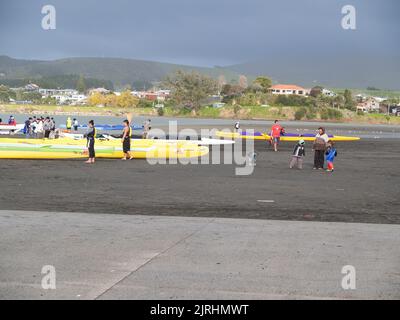 Raglan, Neuseeland - 7 2008. Juni Menschen und Waka-ama oder Kanus am Ufer von Raglan Stockfoto