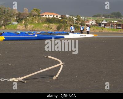 Raglan, Neuseeland - 7 2008. Juni Menschen und Waka-ama oder Kanus am Ufer von Raglan Stockfoto