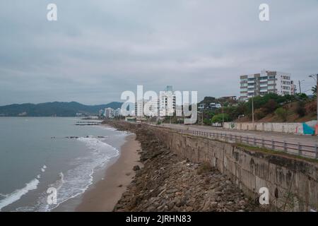 Bahia de Caraquez, Manabi / Ecuador - August 21 2022: Fahrzeuge fahren auf der Allee, die den Strand grenzt, mit einem Panoramablick auf die Stadt auf einer c Stockfoto