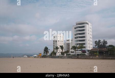Bahia de Caraquez, Manabi / Ecuador - August 19 2022: Menschen gehen und spielen am Strand vor der Promenade mit modernen Eigentumswohnungen in Th Stockfoto