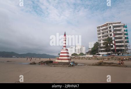 Bahia de Caraquez, Manabi / Ecuador - August 19 2022: Menschen, die in der Nähe des Leuchtturms am Strand vor der Promenade mit einem Modder spazieren und sich ausruhen Stockfoto