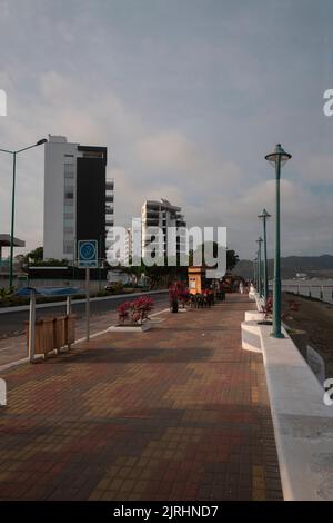 Bahia de Caraquez, Manabi / Ecuador - 20 2022. August: Menschen, die an einem bewölkten Tag auf der Strandpromenade der Stadt am Strand spazieren Stockfoto