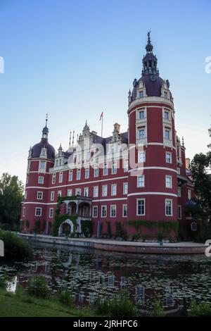 Eine vertikale Aufnahme von Schloss Muskau, die an einem sonnigen Tag in Bad Muskau auf einem Teich reflektiert Stockfoto